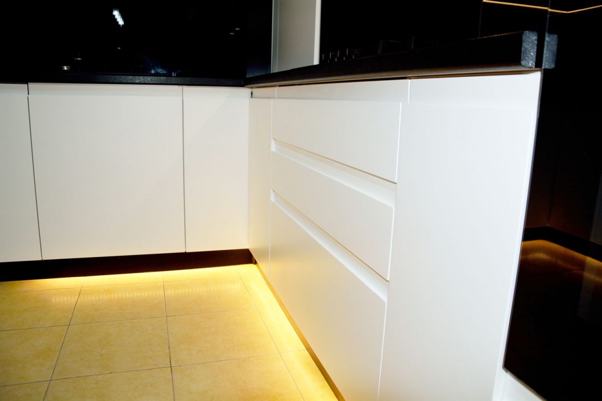 Detaliu usa bucatarie la comanda din MDF vopsit alb mat RAL 9003 cu frezare manare plinta picioare infoliata din pvs si blat termorezistent negru Egger V999 ST89